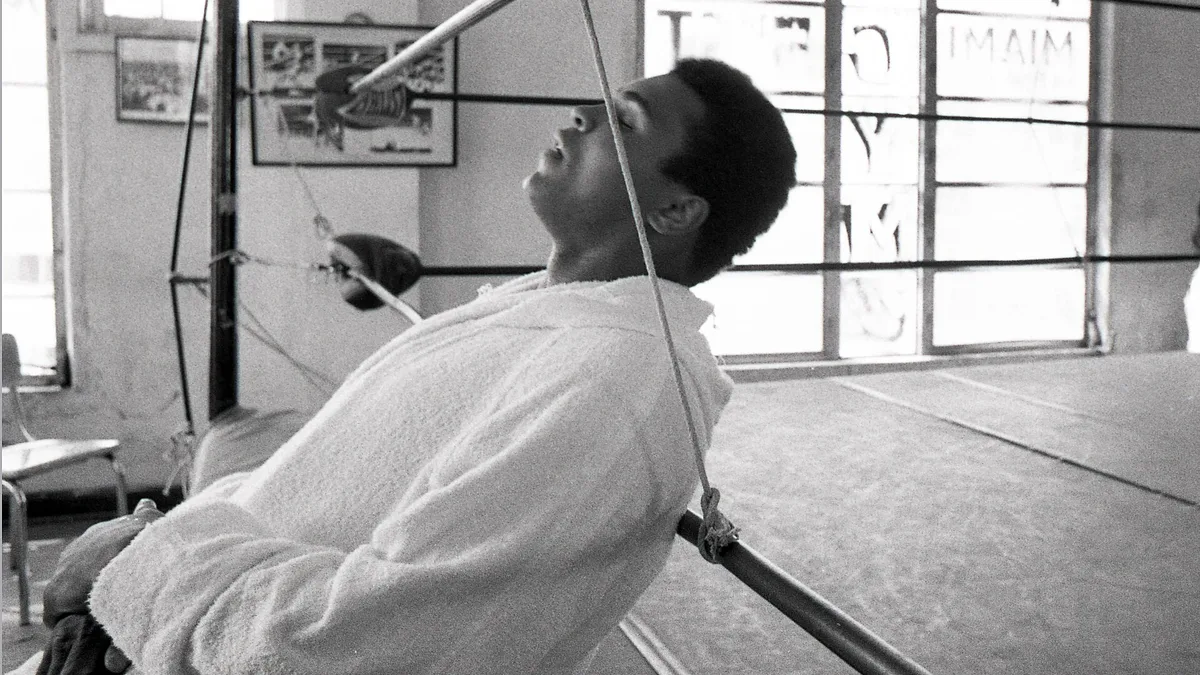 Muhammad Ali resting against the ropes in a towelling robe during a training session, mid-20th century