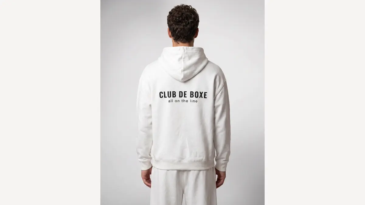 A man wearing the CLUB DE BOXE Heavyweight Essential Hoodie in off-white, seen from behind